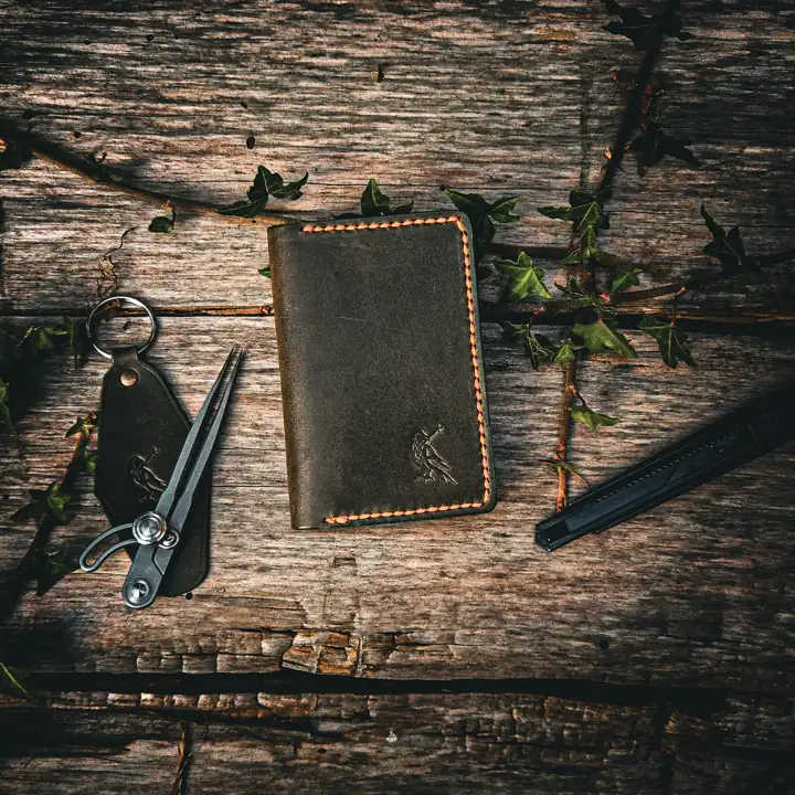 Olive card holder and raven key fob on weathered cedar — Rogue Artisan, East Vancouver